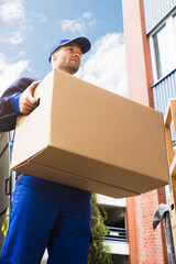 Close-up Of Two Delivery Men Carrying Cardboard Box