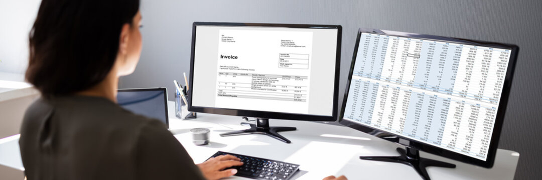 Businesswoman Calculating Invoice On Computer