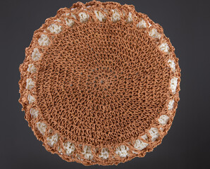 Braided raffia circle. View from above. Handmade beige string bag on grey background. Close-up. Raffia bag. Wicker bag.