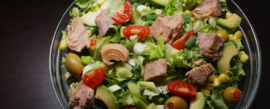 Tuna salad with lettuce, olives, spring onions, cherry tomato, corn and avocado. Canned Tuna fish salad. Food background. Close up. Panoramic image, hi-res banner. Full depth of field.