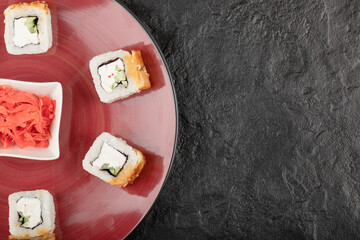 Delicious dragon sushi rolls with eel and pickled ginger on red plate