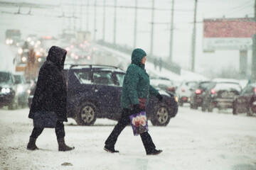 people crossing the road in stormy snowy weather at shallow depth of field