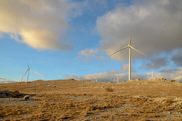 Wind farm on the mountain at sunset. Wind turbines on the hill. Renewable energy. Wind park.