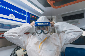 young sanitary woman puts on a protective suit against viruses in an ambulance © Javier Gea