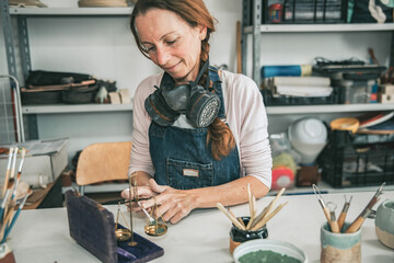young artisan woman working with her hands a piece of ceramic mixing colors