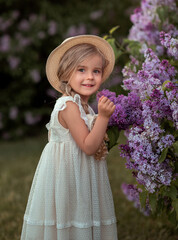 little girl in a straw hat holding a bouquet of lilacs. Girl with flower. Девочка с цветами