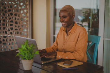 black adult woman works on her computer and does video conference in a coffee shop focus on the face