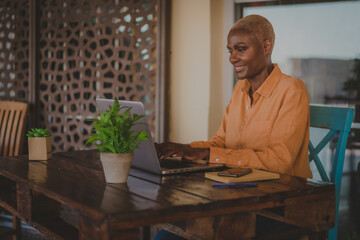 black adult woman works on her computer and does video conference in a coffee shop focus on the face