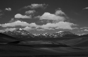 Alpine landscape in black and white. View of the Andes mountain range, desert, sand and mountain peaks under a beautiful sky with clouds. 