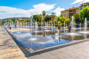 Tourists and local French enjoy a sunny day at Promenade du Paillon water feature in the town square center of Nice, France, on the French Riviera.