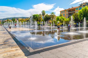 Fotobehang Nice Tourists and local French enjoy a sunny day at Promenade du Paillon water feature in the town square center of Nice, France, on the French Riviera.