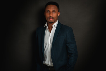 Portrait of attractive, handsome, pretty, serious and stylish professional african american businessman executive with stylish suit and white shirt isolated on dark background. Low key. Selective focu