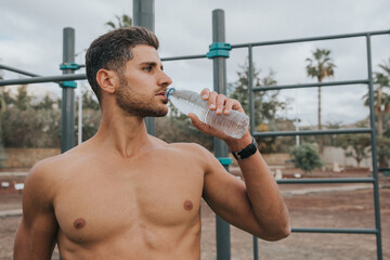 Fototapeta na wymiar young man exercises with face mask outdoors and drink water