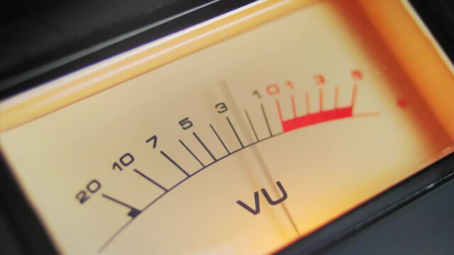 Close up full frame a highlighted analog VU meter with moving needle. A classic symbol of audio recording and music