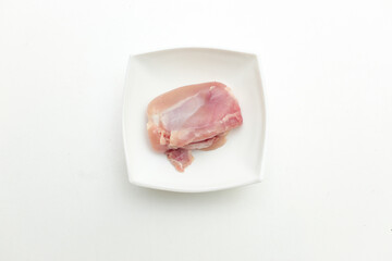 Raw bright chicken thigh in white plate isolated on white background