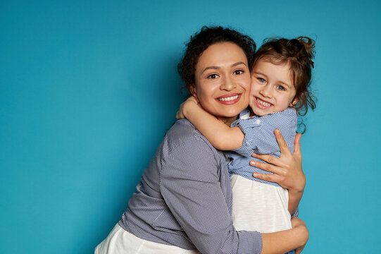 Cheerful mother hugging her daughter. Blue background, happy mother's day concept, Children protection day