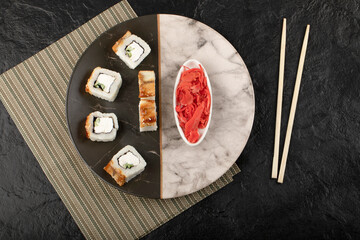 Dragon sushi rolls with eel and pickled ginger on marble plate