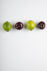 Two lime fruits and fresh plums on white background
