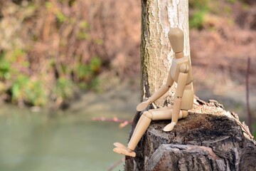 Maniquí de madera sentado en un tronco, junto al río