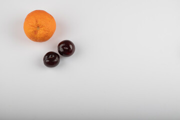 Delicious ripe plums with whole orange on white background