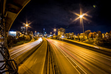 Fototapeta na wymiar Streaks of lights as cars drive on the highway towards a big urban city downtown area in Chicago.