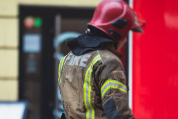 Fototapeta premium Group of fire men in uniform during fire fighting operation in the city streets, firefighters with the fire engine truck fighting vehicle in the background, emergency and rescue