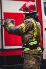Group of fire men in uniform during fire fighting operation in the city streets, firefighters with the fire engine truck fighting vehicle in the background, emergency and rescue