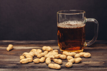 mug of beer on a wooden table peanuts in shells alcohol drink close-up