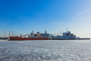 Massive different ship vessels trapped in ice tries to break and leave the bay between the glaciers, icebreaker and carrier vessel, winter blue sky view