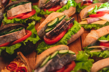 Beautifully decorated catering banquet table with different food snacks and appetizers with sandwich on a wooden plate, on corporate christmas birthday kids party event or wedding celebration