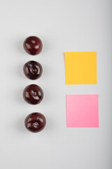 Delicious cherry plums and two memo pads on white background