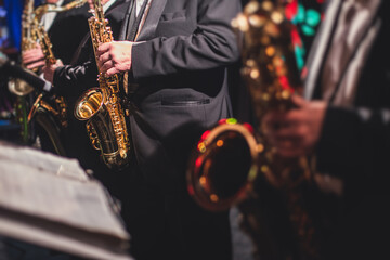 Obraz premium Concert view of a saxophonist, saxophone sax player with vocalist and musical during jazz orchestra performing music on stage