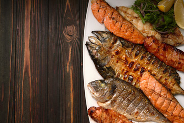 Grilled fish on a white plate with herbs and lemon, dorado, mackerel, salmon steak, salmon fillet, on a wooden board