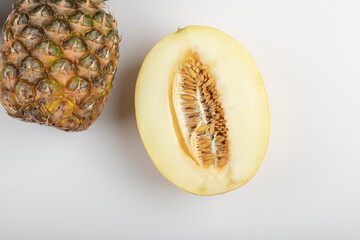 Halved melon and ripe delicious pineapple on white background