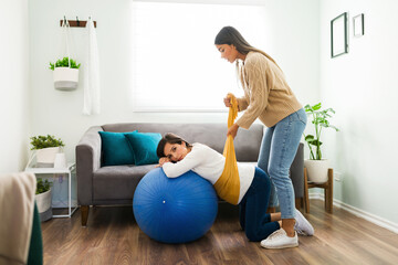 Hispanic doula lifting the belly of an expectant mother with a rebozo