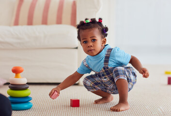 cute african american baby girl playing toys at home