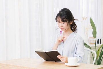 部屋でノートにメモを書く若い女性