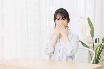 部屋で驚いたジェスチャーをする若い女性
