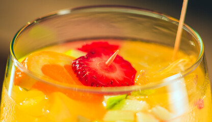 close up of Refreshing yellow cocktail with fruits in glass on sunny day in front of the sea