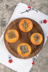 Delicious ripe persimmon fruits placed on wooden plate