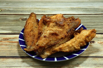 Pile of deep fried Grouper fish fillet (Sea basses) seasoning with flour and pepper serving on the plate. 