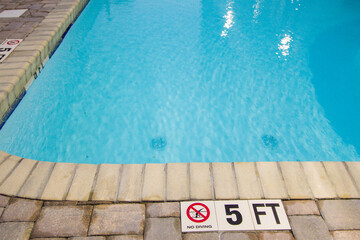 Warning sign of no diving into the shallow end of a swimming pool.