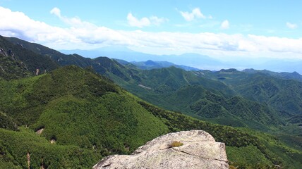 瑞牆山（みずがきやま）　山頂からの眺望、緑の山々。足元には巨岩。奥秩父・山梨県北斗市にある山、百名山の一つ。花崗岩で形成され、頂上付近は岩がむき出しとなっている、