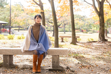 秋の公園にたたずむ女性
