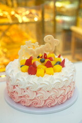 Birthday cake decorated with flower-shaped cream sold in a cake shop, with mango, strawberry and blueberry on the cake, vertical picture