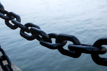 Closeup of black iron chain and water background, safe protection and copy space