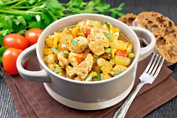 Chicken with vegetables and peas in saucepan on table