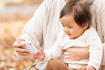 公園でスマホで遊ぶ親子
