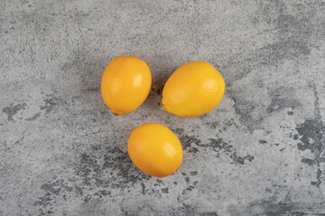 Three fresh yellow lemons placed on stone surface