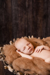 2. Newborn baby girl sleeping on a wool blanket in a wooden basket